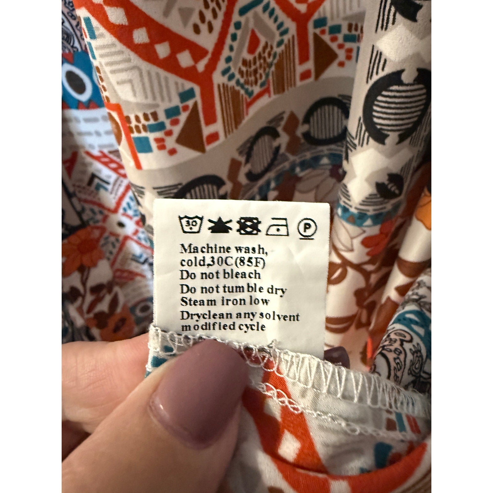 This is a bohemian-style floral geometric orange and tan button-down shirt dress or long cardigan